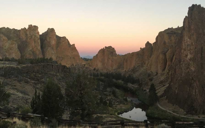Large rock formations just upward amongst trees and a small body of water.